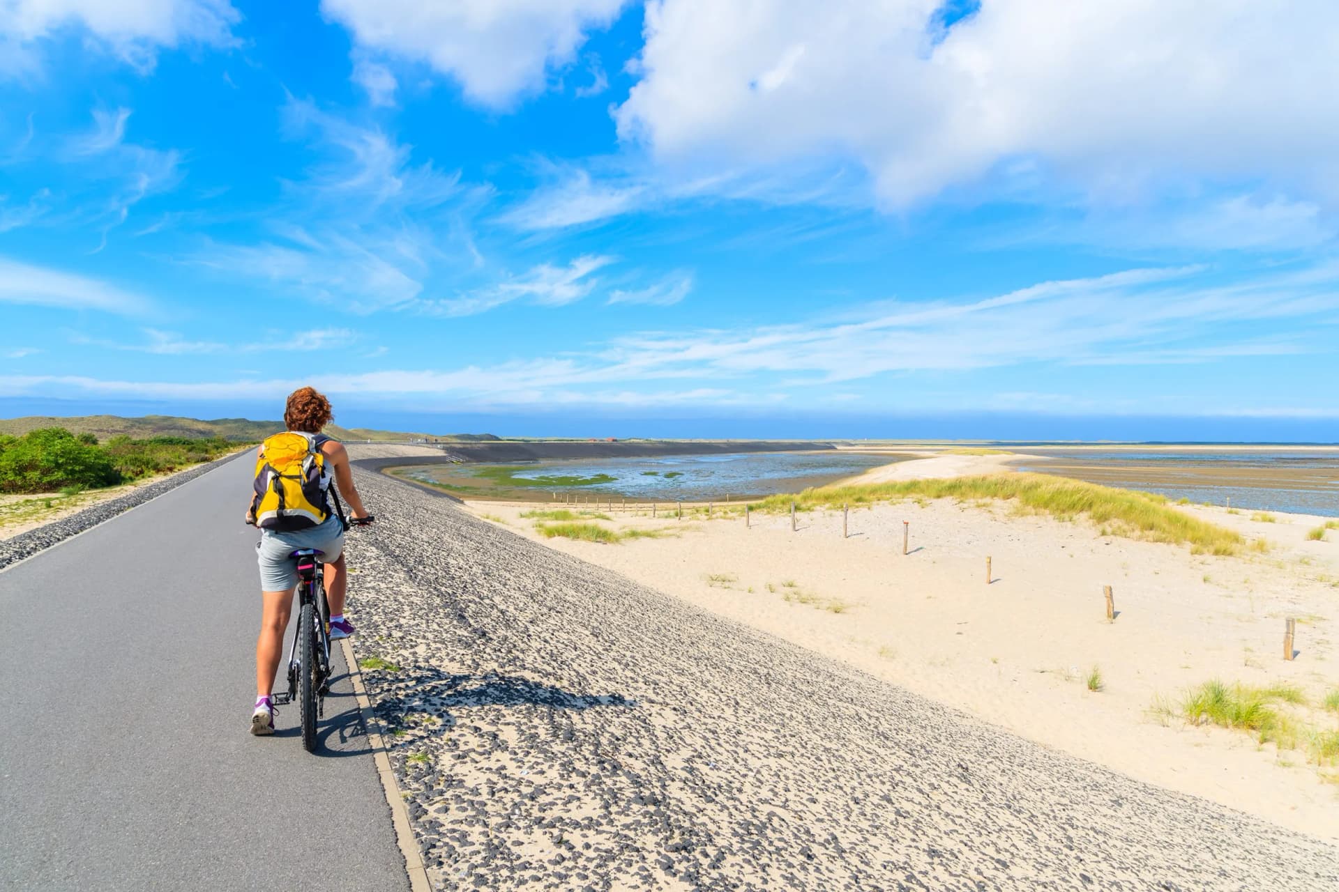 Young woman on bike during trip along coast of Sylt island near List village, Germany.