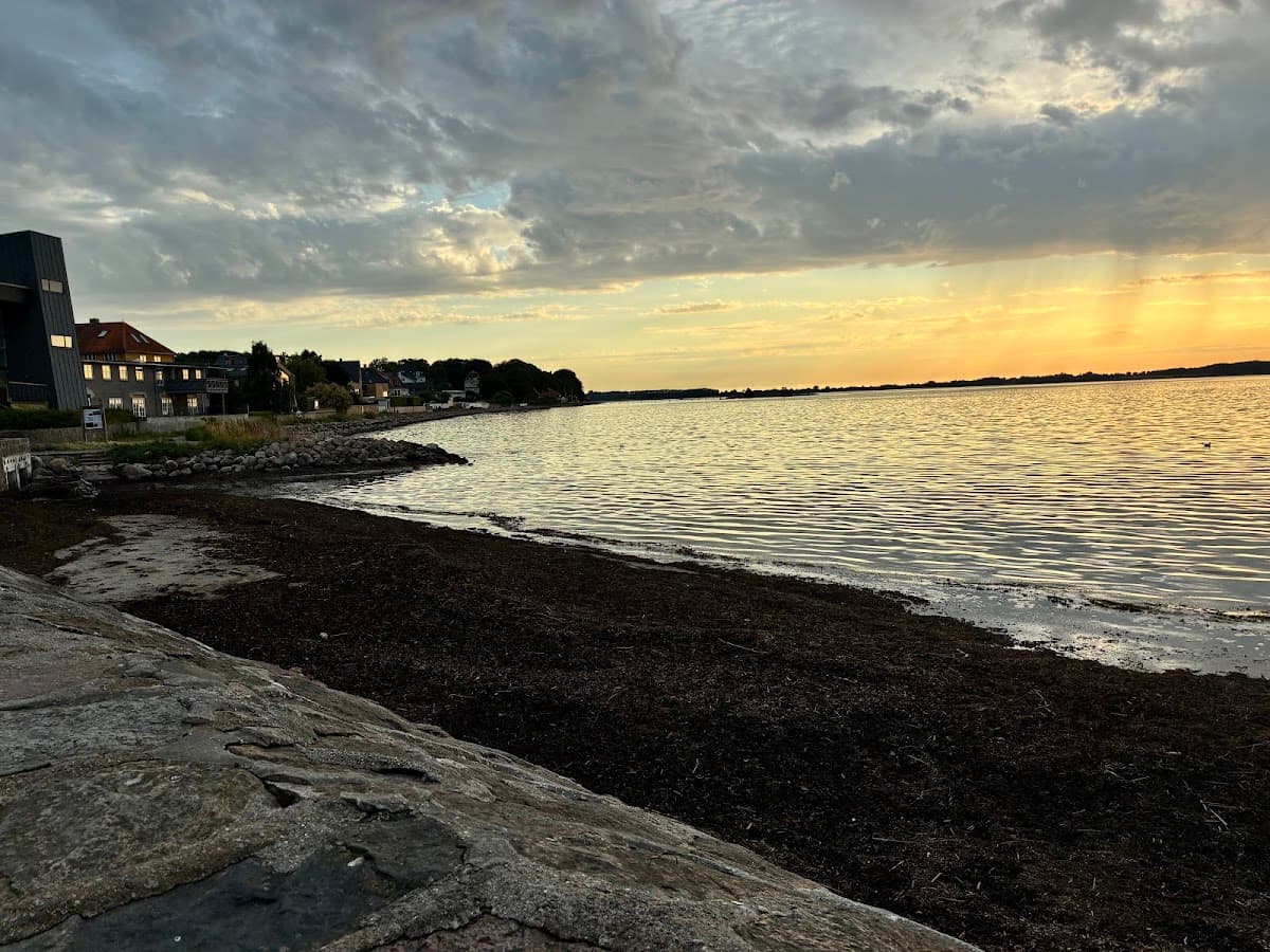 Coastal shoreline at sunset with buildings along the water and cloudy sky