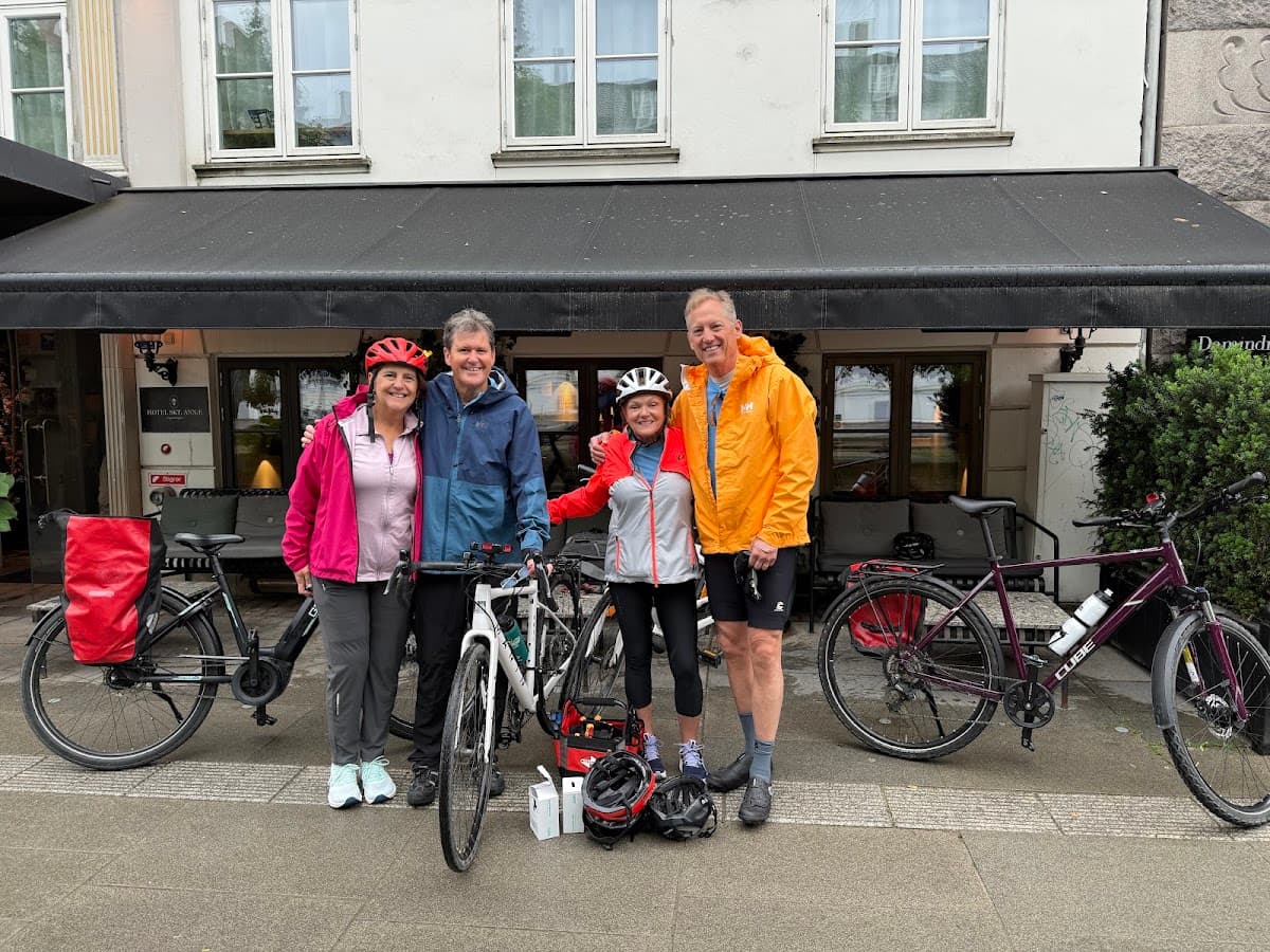 Group of cyclists with touring bicycles standing on a sidewalk in front of a building